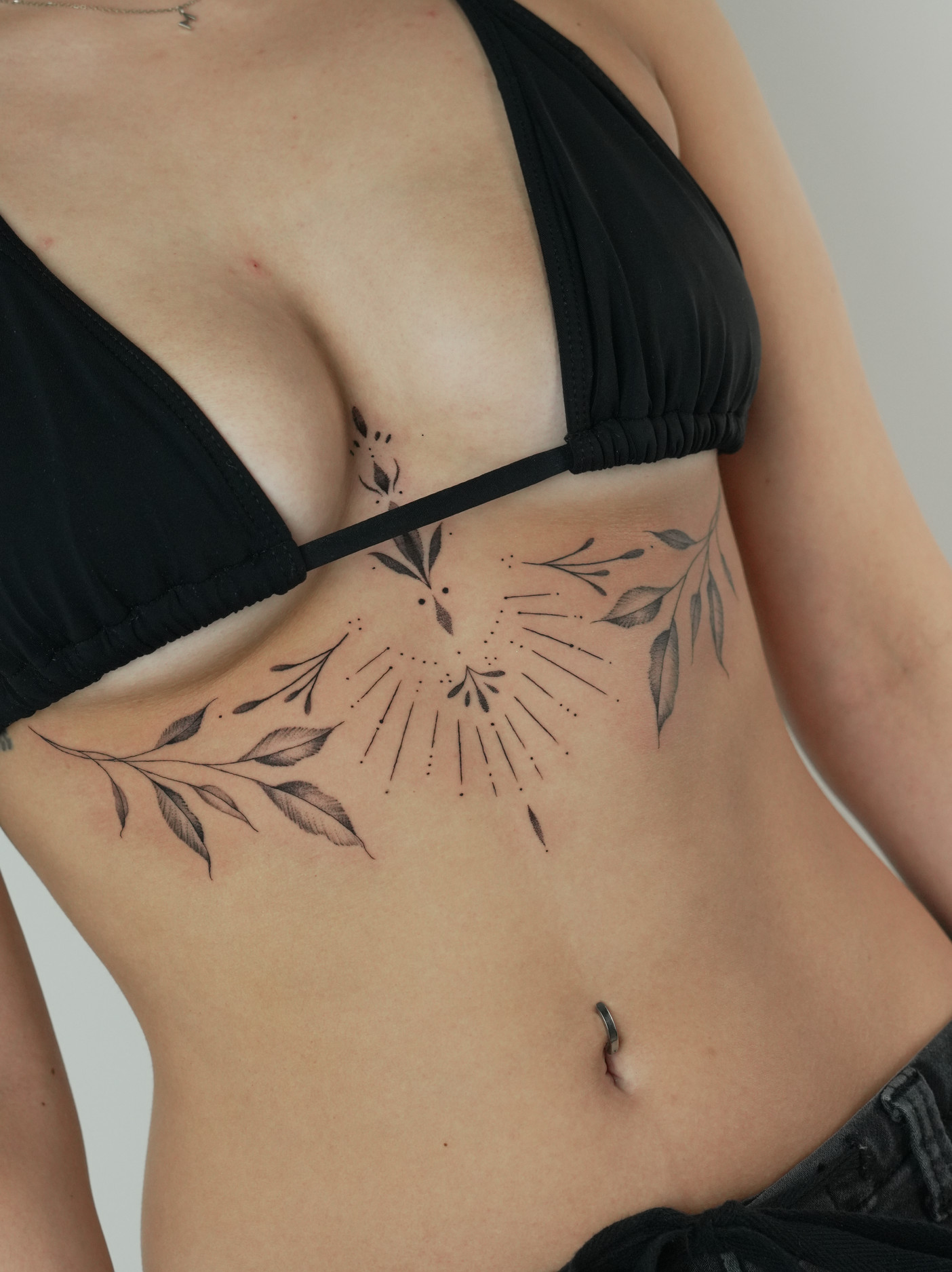 Fine line botanical sternum tattoo with dotwork